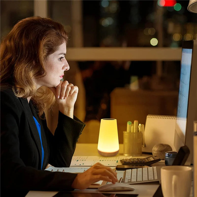 Woman working at desk with OSITE SKY color-changing night light illuminating workspace beside computer.